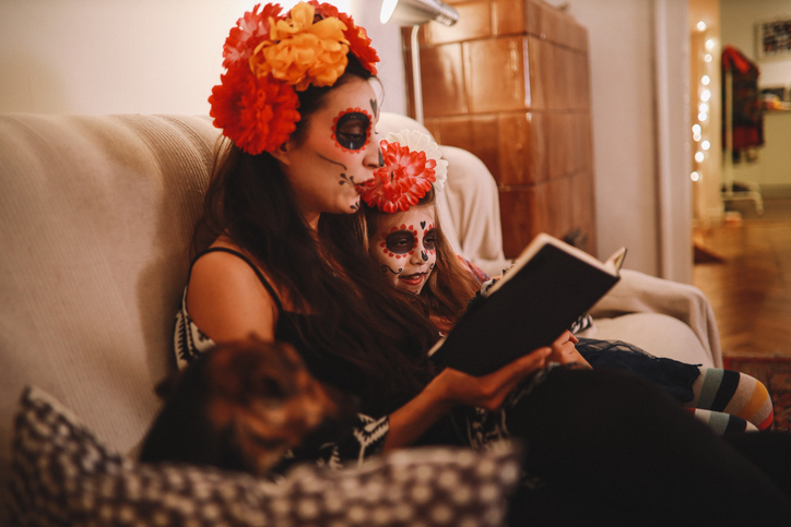 Parent dressed as catrina reading to child also in catrina makeup
