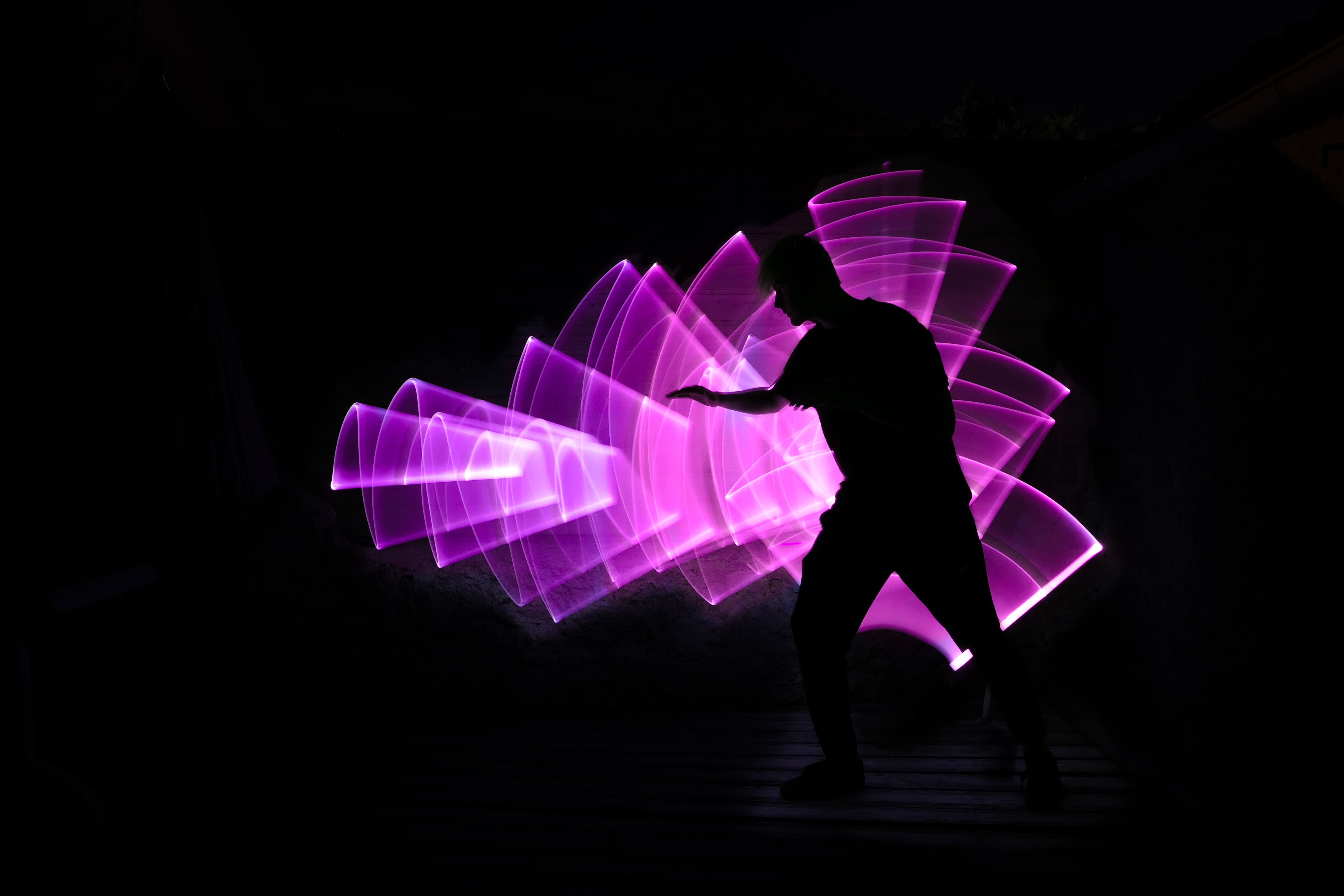 Silhouette of a person against art made my capturing light with long-exposure photography.