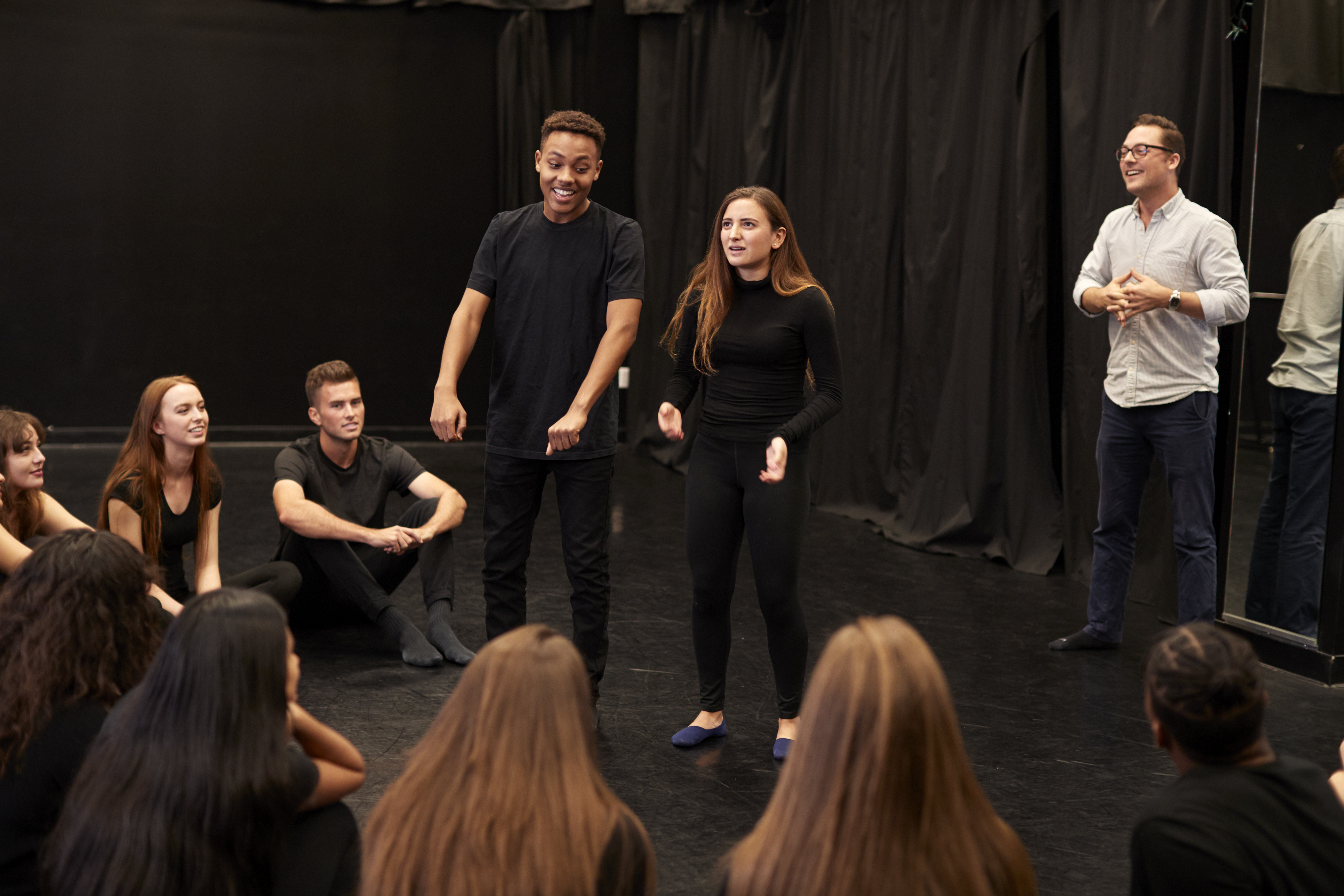 Teens on a stage practicing acting and theater exercises.