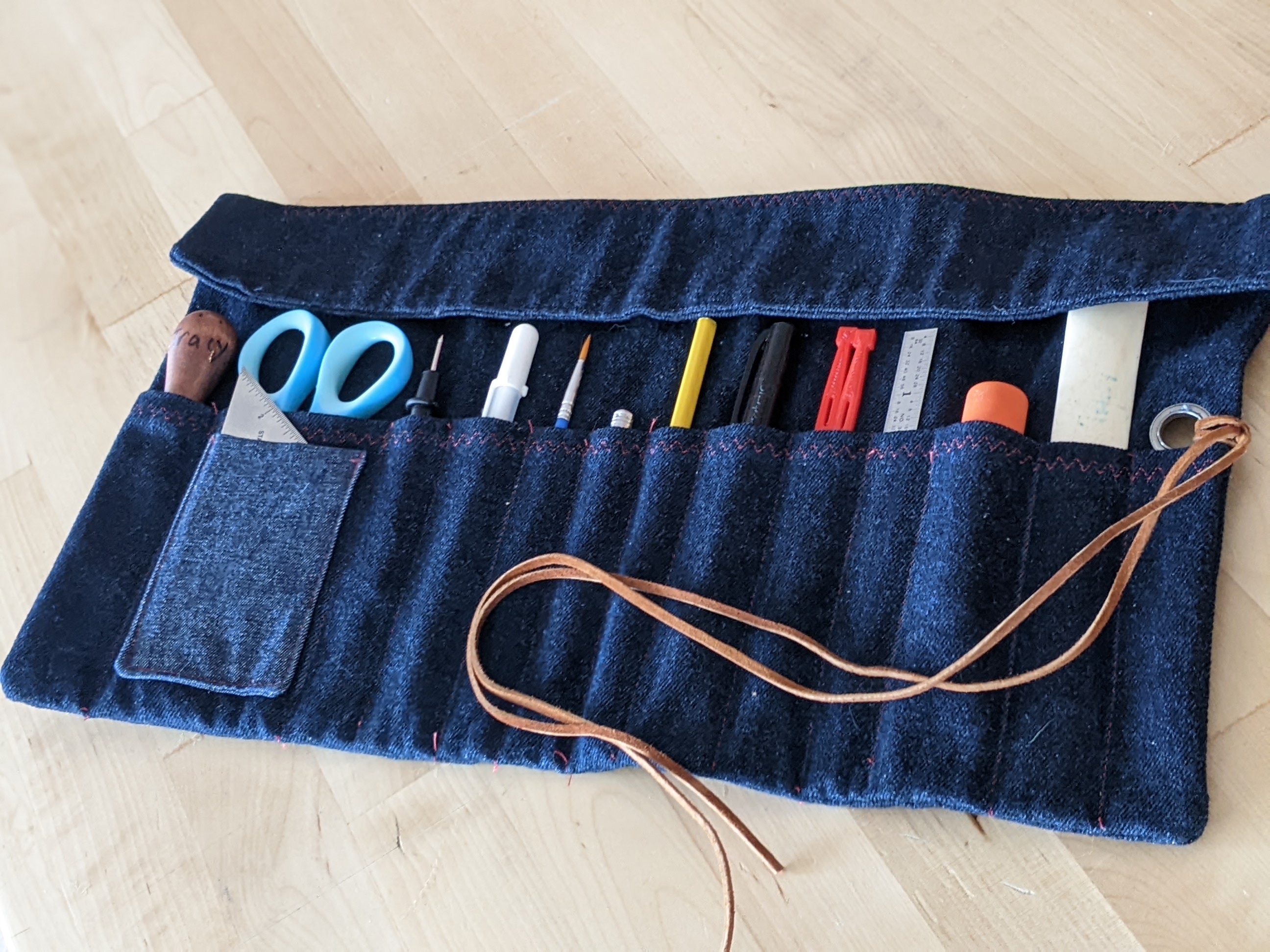 Denim handmade tool roll with tools and a leather strap
