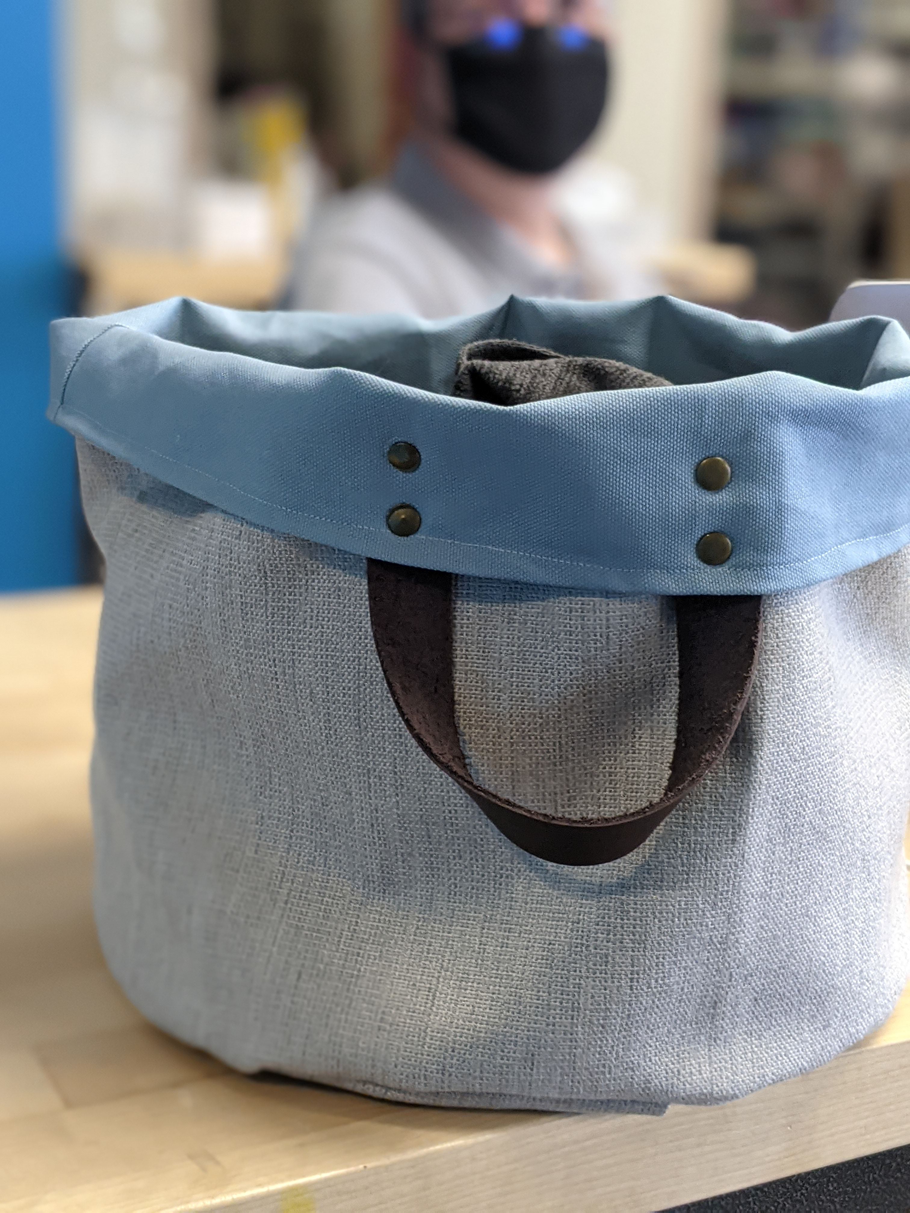 Close up of a fabric bucket tote bag with leather straps on a table.