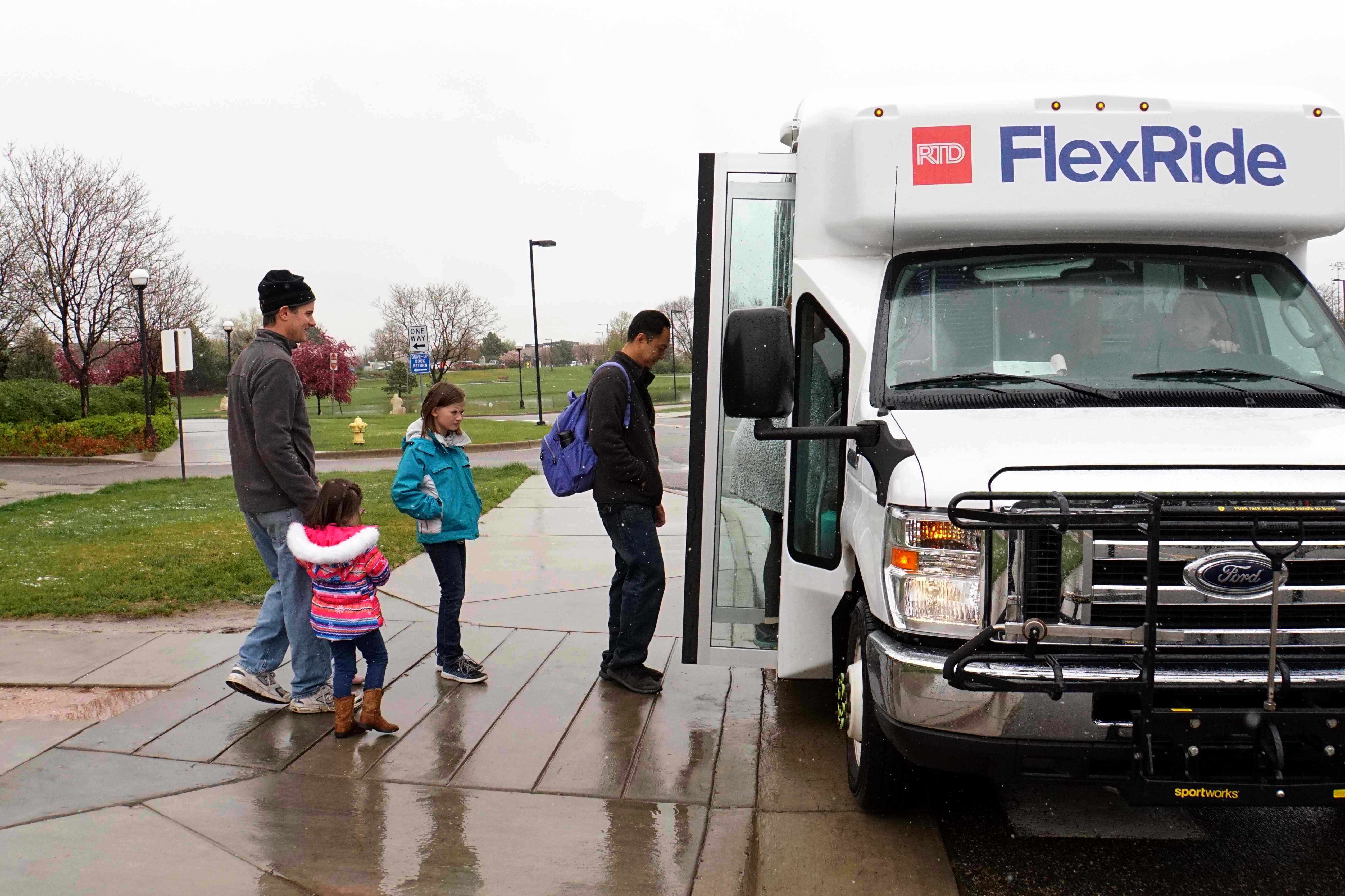 Kids and adults waiting in line to board the FlexRide bus.
