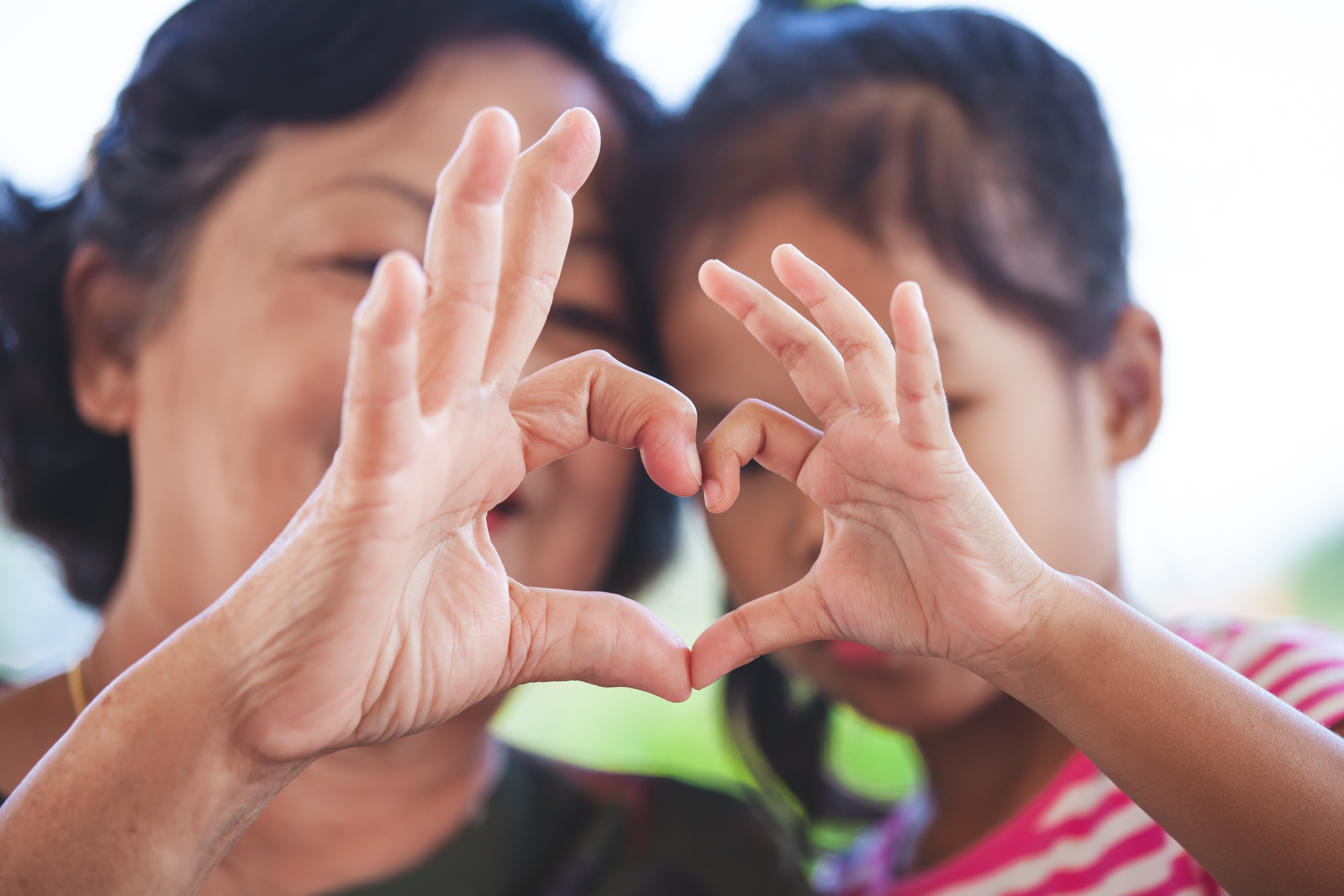 Adult and child making a heart shape with their hands