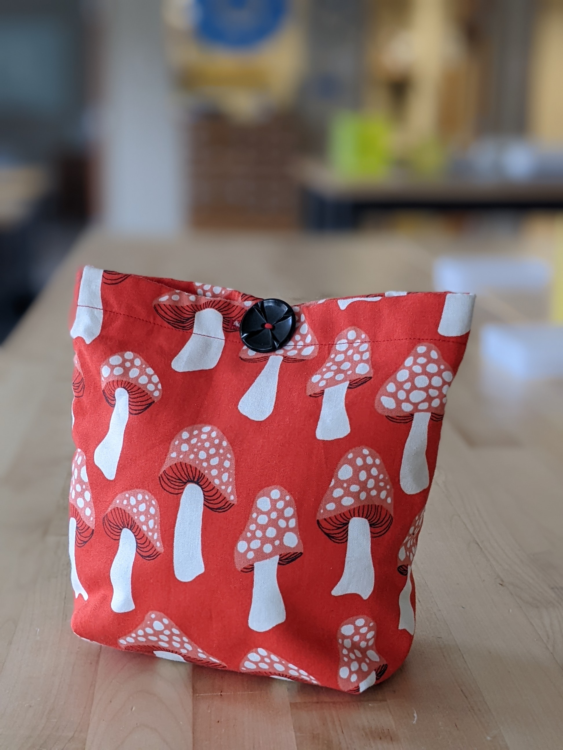 Red and white fabric bag with gusset corners and button closure. 