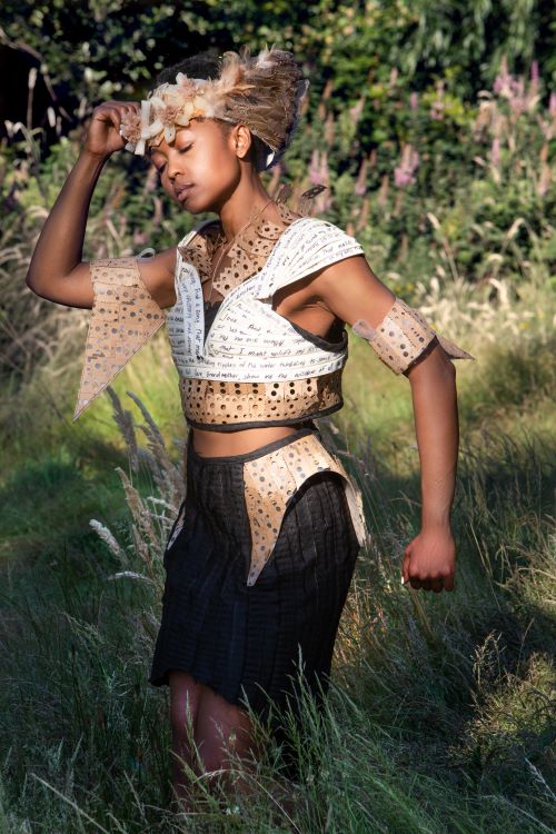 Model wearing upcycled costume made from paper standing in a field