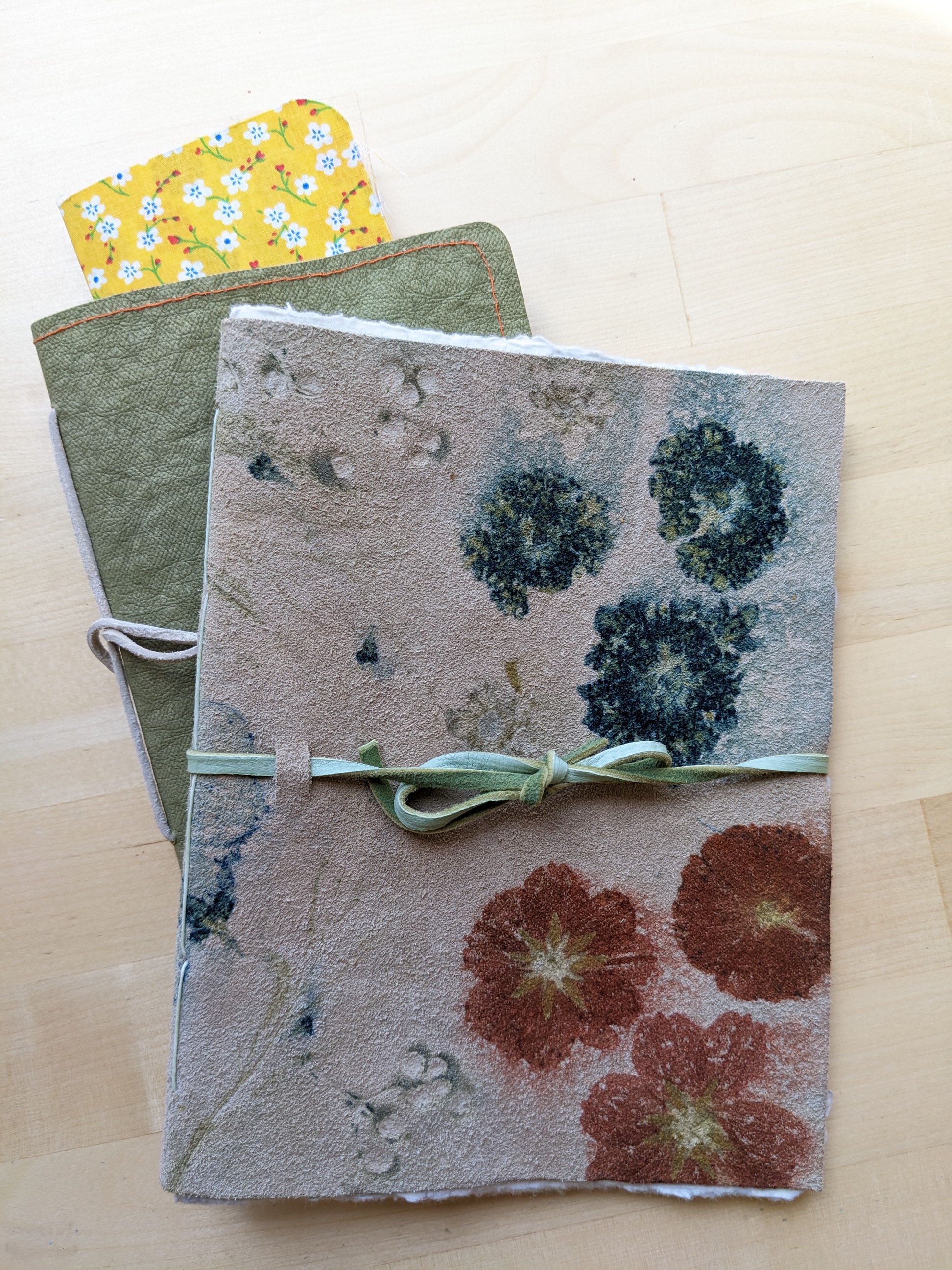 Three different journals with the same pamphlet stitch binding. Top journal is flower pounded leather.