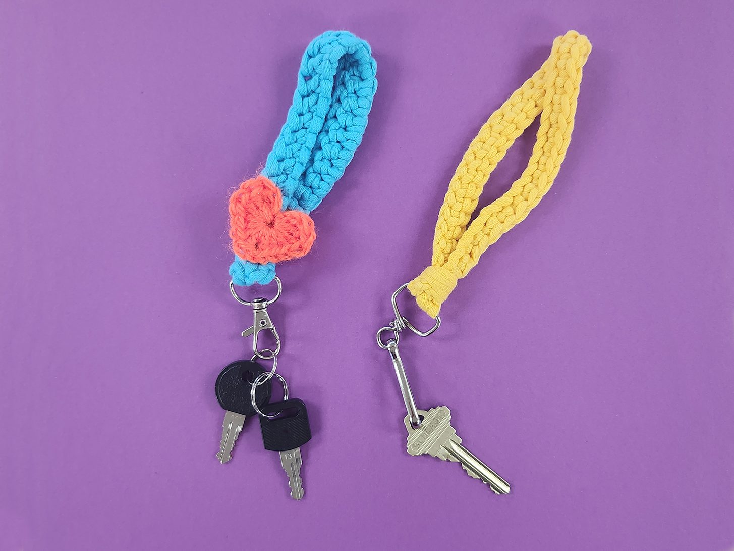 Crochet keychain lanyards with keys on a purple background. Left is blue yarn with an orange heart detail and right is a bright yellow lanyard.