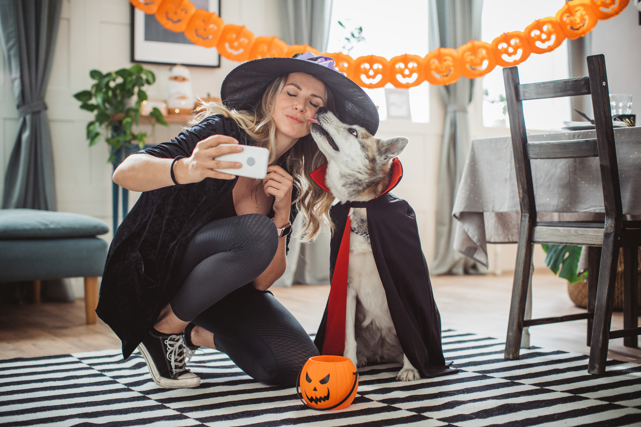 human dressed as witch with dog dressed as vampire