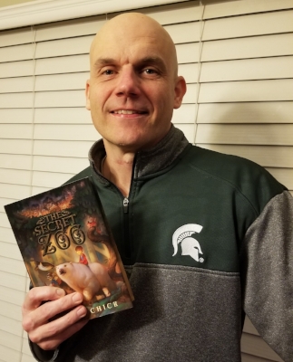 Author Bryan Chick holding a copy of The Secret Zoo