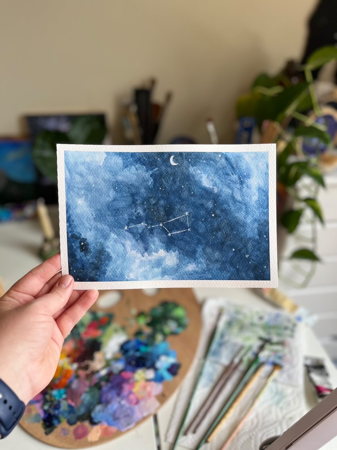 picture of artist holding watercolor constellation painting