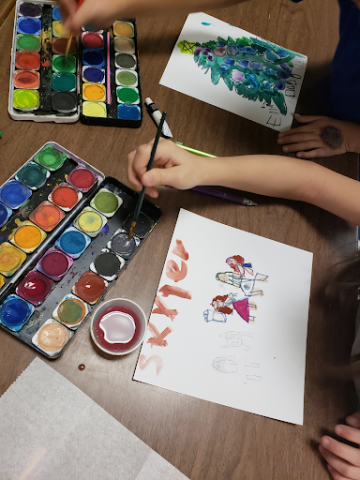 Kids using watercolor paints to write their names and family stories