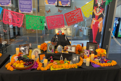 community ofrenda table with papel picado, candles, and marigolds