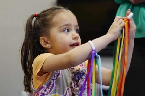 Young girl dancing with colorful ribbons
