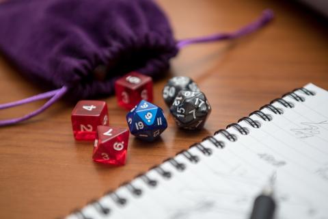 D&D dice with bag and notepad with pencil.