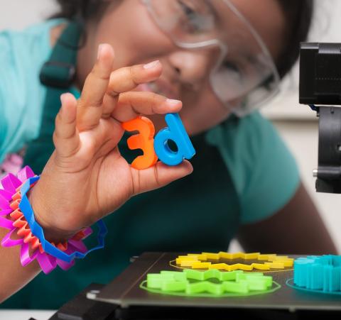 Teen holding 3D printed letters and wearing 3D printed bracelets