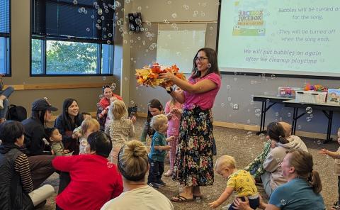 Librarian sharing bubbles from a bubble machine with babies and their families.