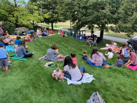 Storytime outside.  Families sitting on blankets in the grass.