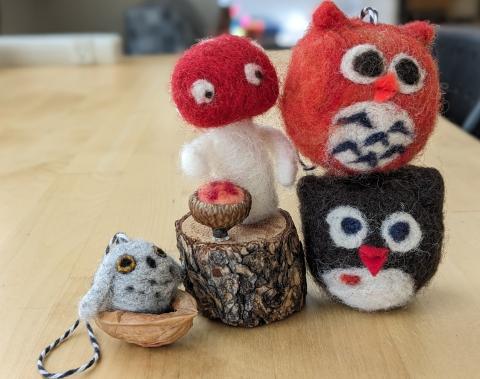 Needlefelted miniature owls and a mushroom on a table.