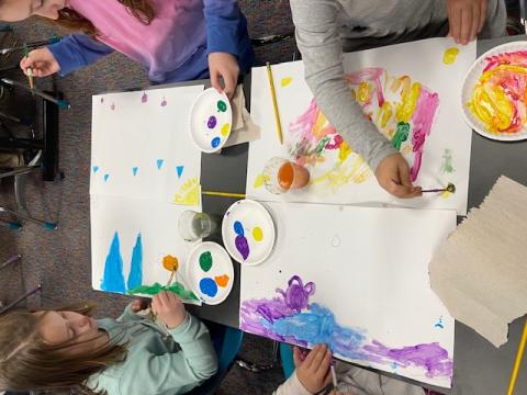 children painting on white paper at a table.
