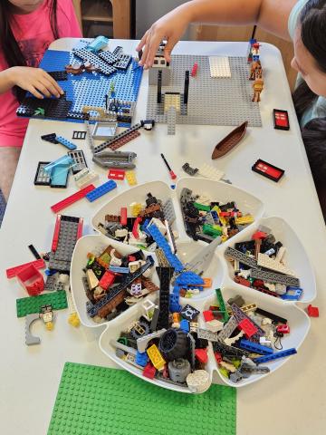 children playing with LEGOs at a table full of LEGOs.