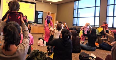 Children being lifted up by their caregivers during a storytime song