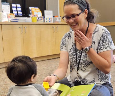 Adult and child looking at a book and using sign language together