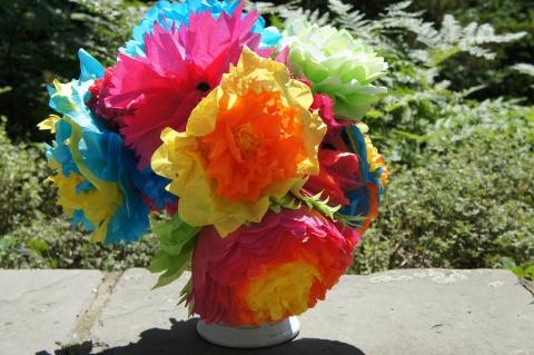 Bouquet of colorful tissue paper flowers arranged in a vase placed in an outdoor setting
