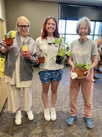 three women holding potted house plants