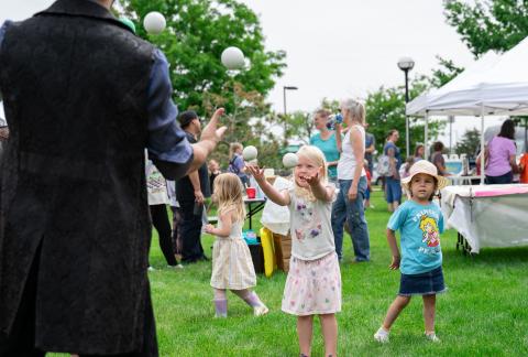 Kids laugh while catching juggling balls at outdoor community event