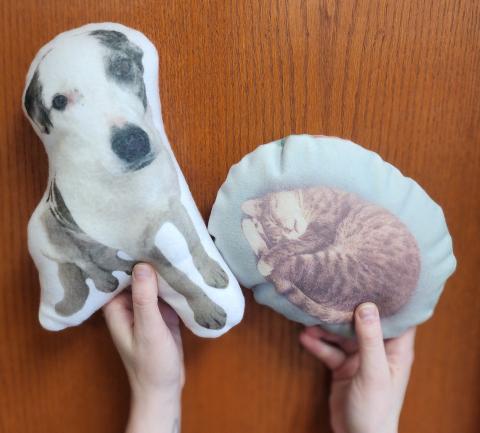 Hands holding sublimation printed pillows featuring a dog and a cat