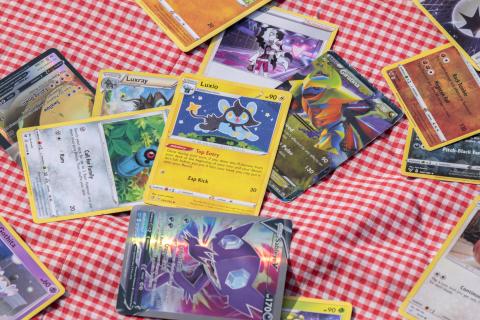 A variety of Pokemon cards laying on a checkered tablecloth.