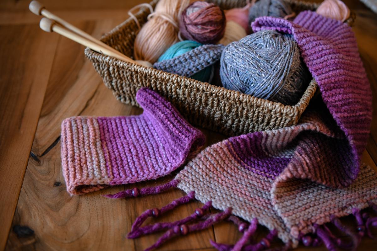 a wicker basket of yarn and knitting needles