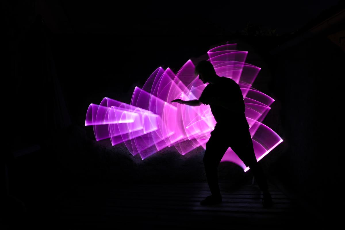 Silhouette of a person against art made my capturing light with long-exposure photography.