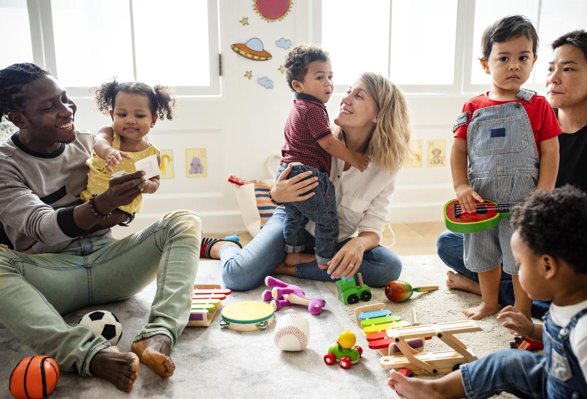 Babies, Toddlers and their caregivers playing with colorful toys.