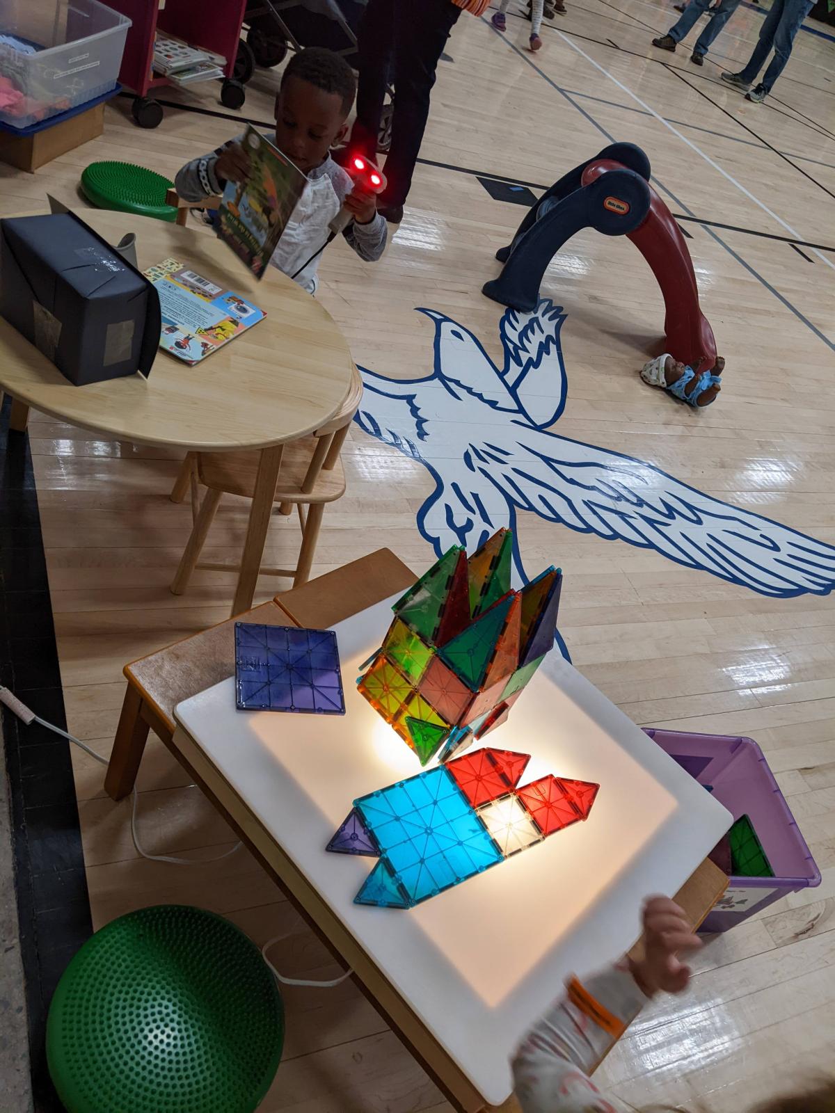 Light box table with multiple colored Magna Tiles, small slide and book scanning station for kids