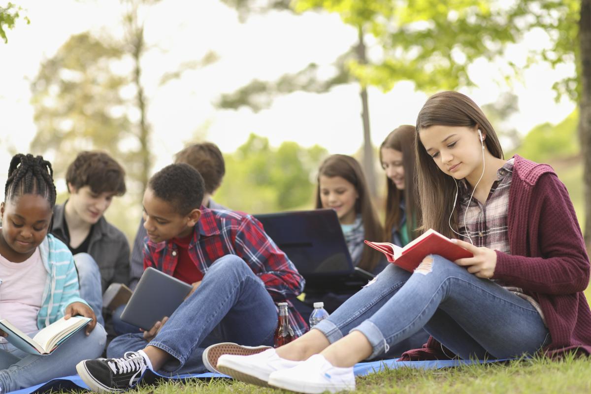 Group of Middle Schoolers sitting outside reading.