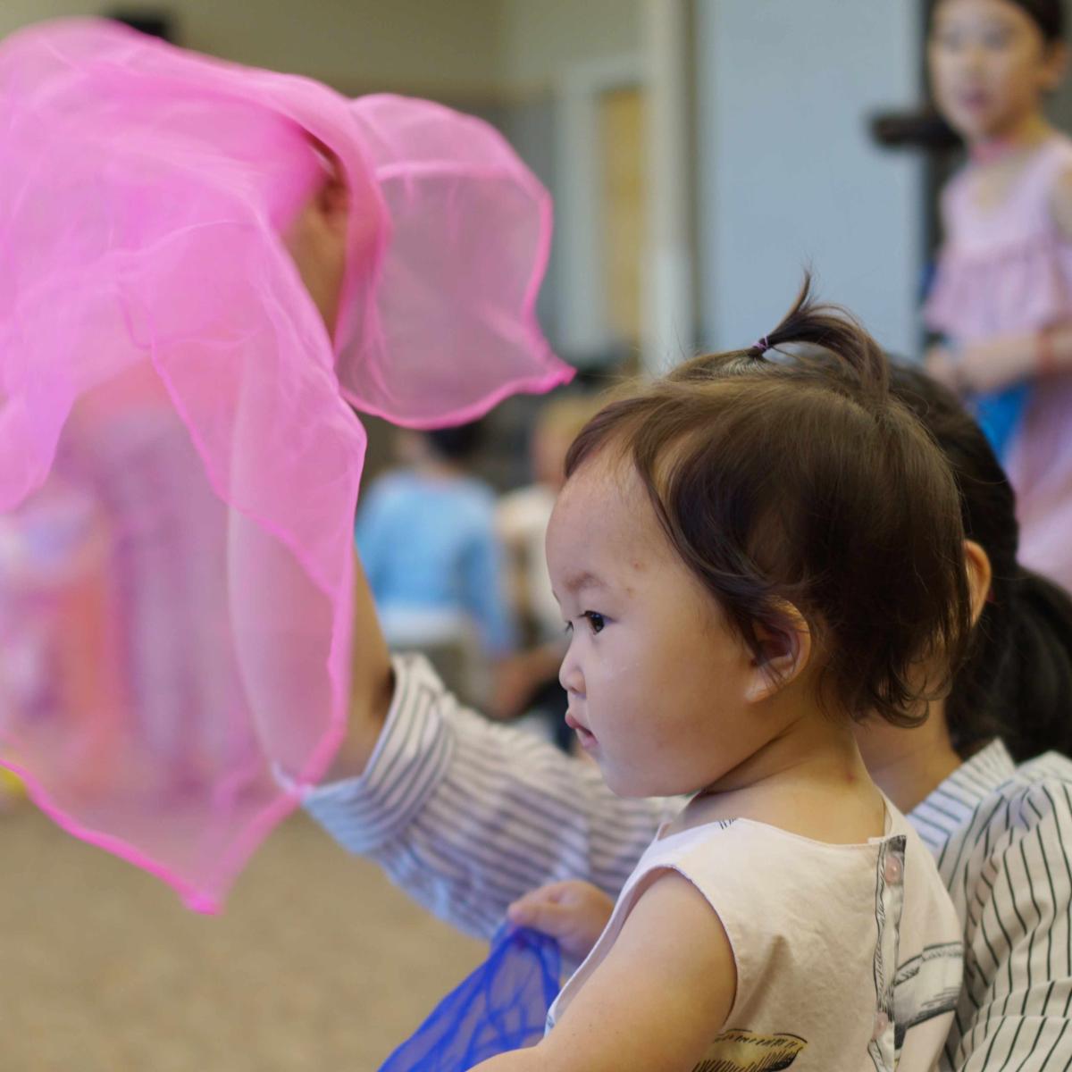 Toddler and caregiver dancing with a pink scarf