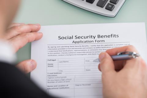 Showing hands filling out a Social Security Benefits application