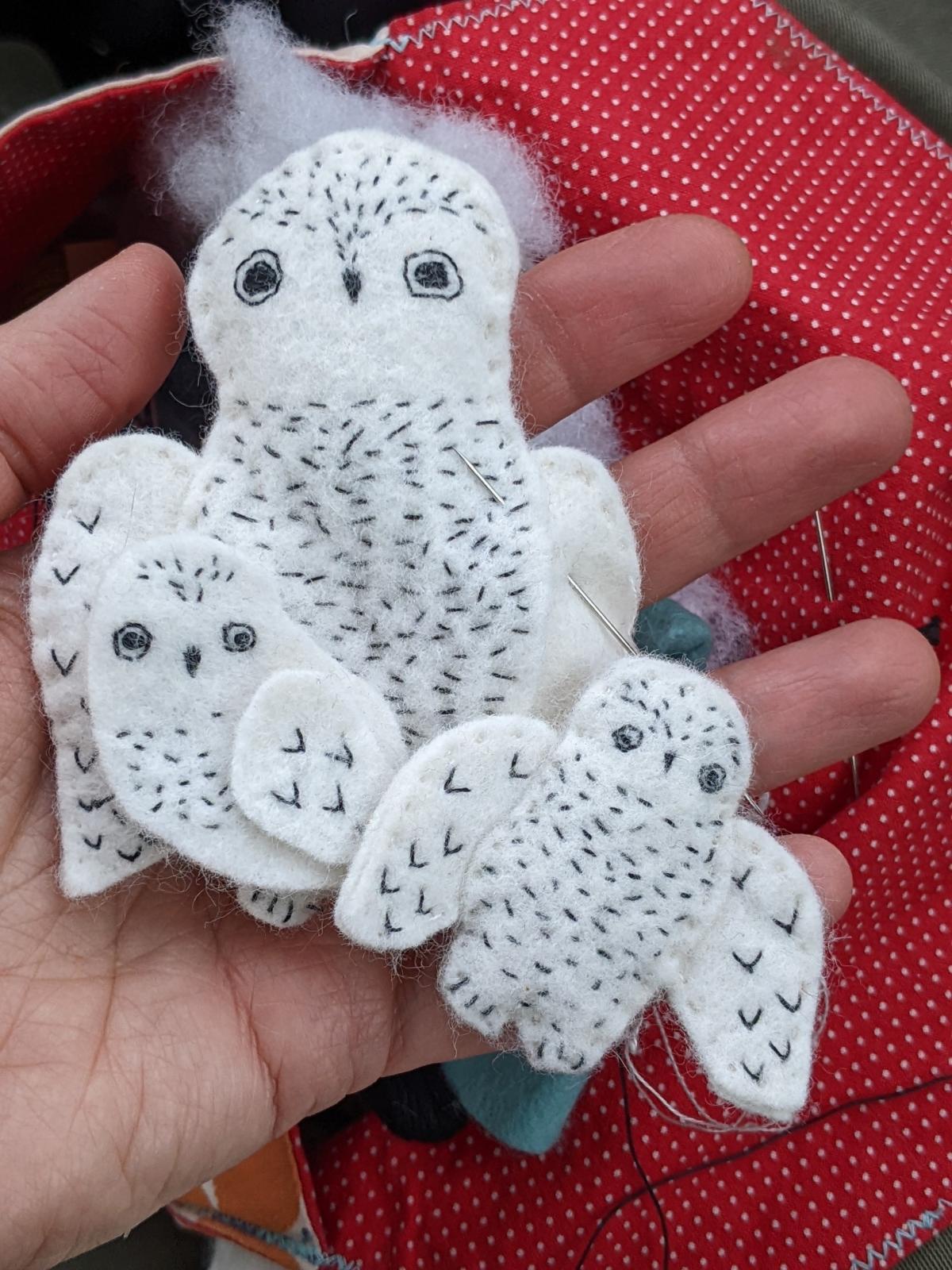 Large owl with two little owls made from white felt with small black hand stitches.