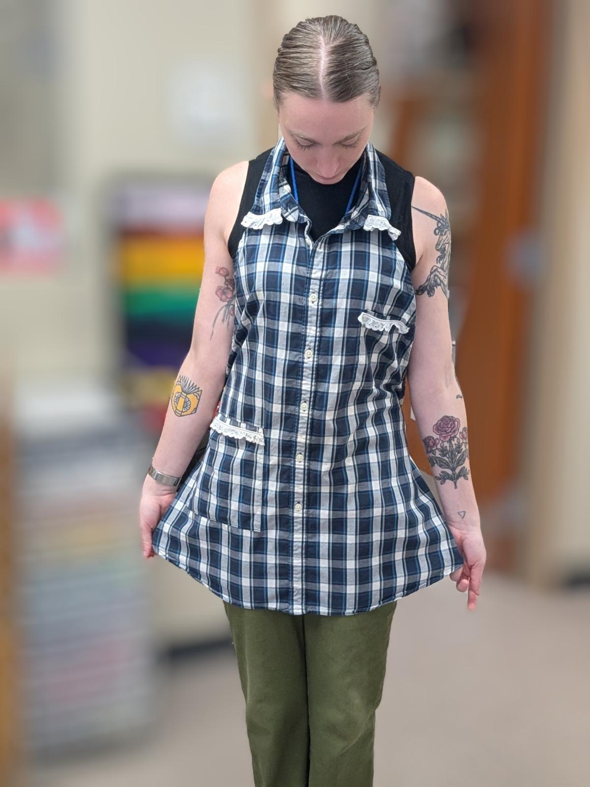 Woman modeling an apron made from an upcycled plaid button up shirt.