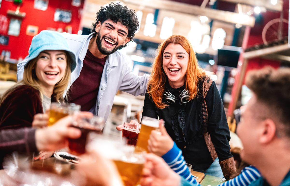 Young professionals at a brewery enjoying drinks and laughing