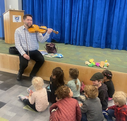 Adult playing violin for group of young children