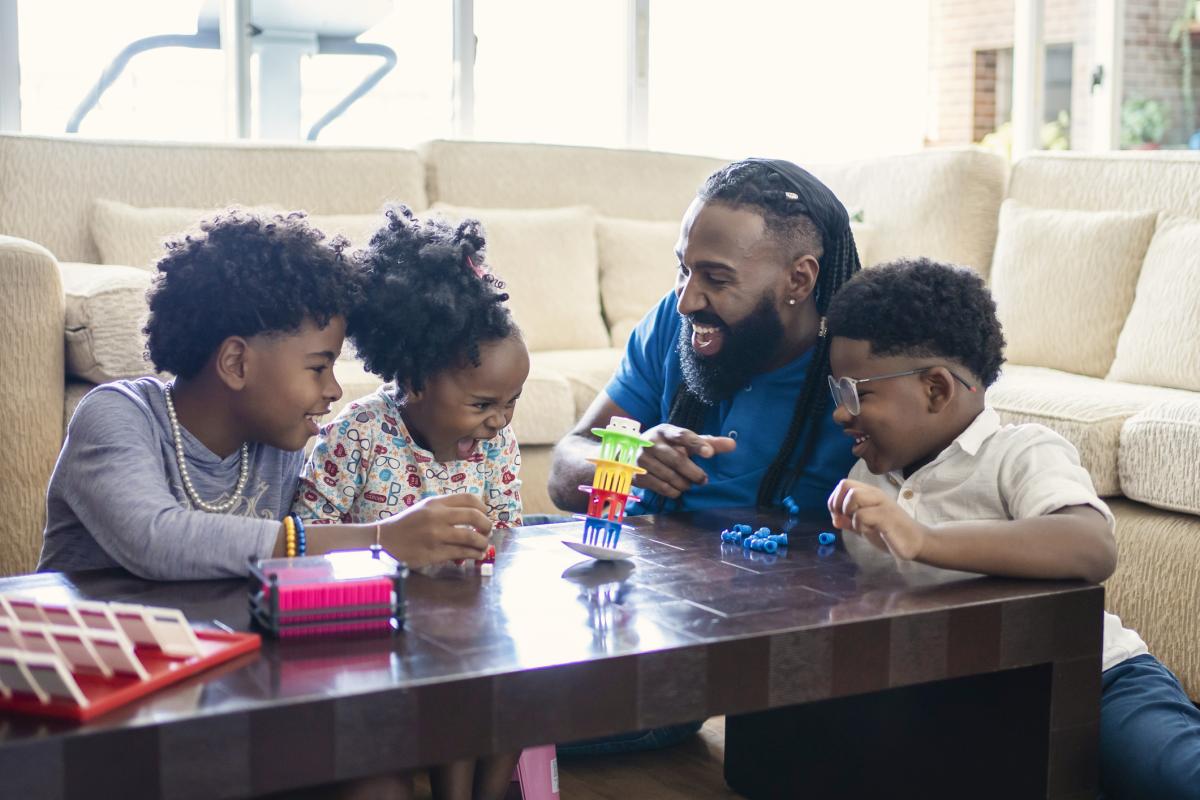 Parent playing table game with three children
