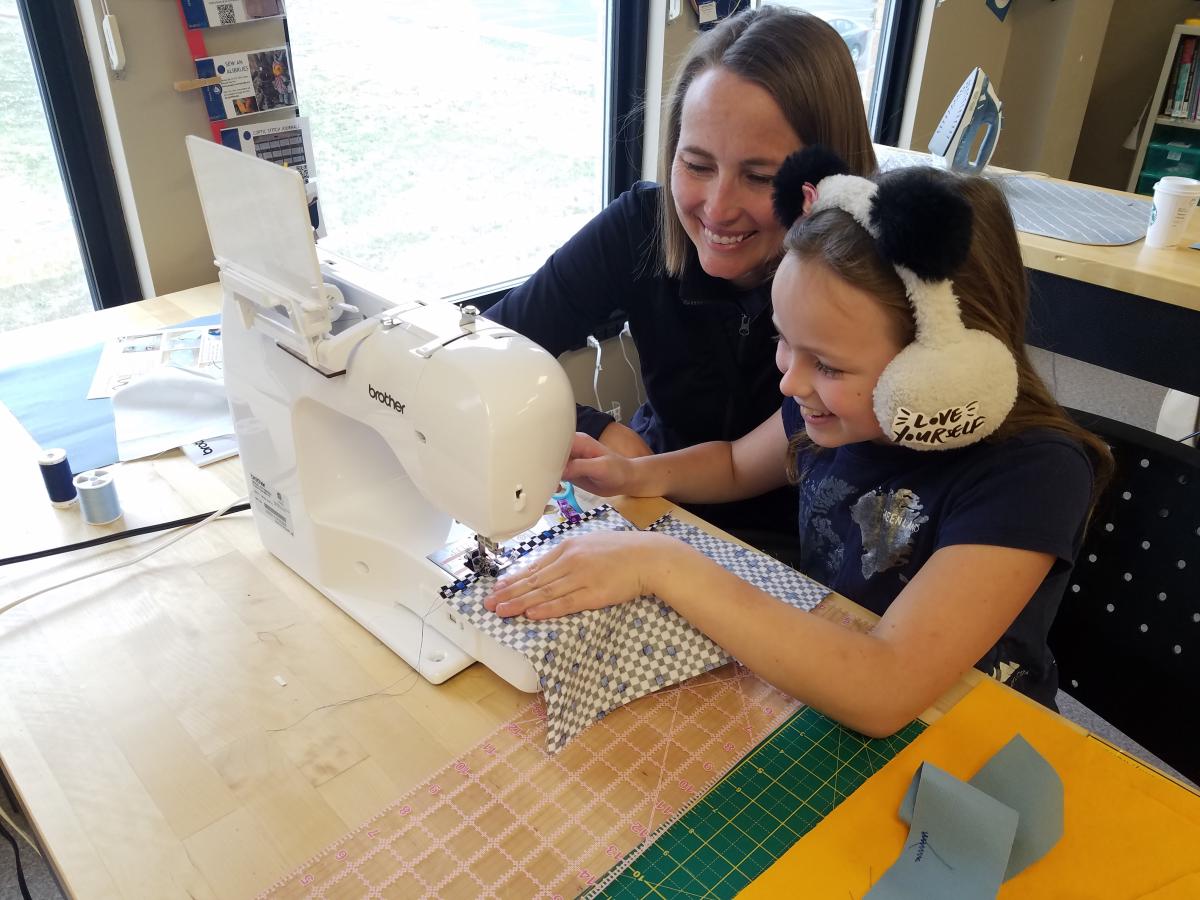 Parent and child working together on a sewing machine